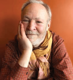 Headshot of a man wearing a red button-down shirt and a yellow scarf, looking at the camera.